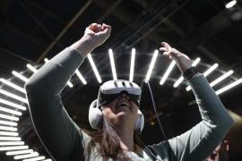 Un asistente usa gafas de realidad virtual para experimentar una plataforma de metaverso “hiperrealista” en el stand de Lotte Data Communication y Caliverse en el CES 2024 en Las Vegas.