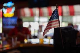 Una bandera estadounidense, en la caja registradora del bar Fricker's en Springfield, Ohio, el 30 de septiembre de 2026, mientras los miembros del sindicato UAW Local 402 toman un trago en el último día de la antigua Navistar en su planta de Springfield.