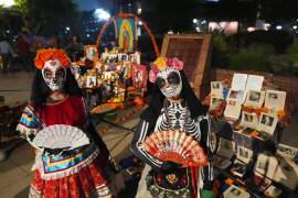 Gente junto a puestos de la calle Olvera en una procesión nocturna durante el Día de Muertos en Los Ángeles.