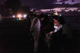 Gente pasa la noche en la oscuridad en el Malecón durante un apagón en La Habana, Cuba.