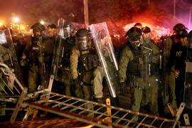 Policías derriban una barricada durante un enfrentamiento con manifestantes cerca del centro de detención Delaney Hall, durante una protesta contra el traslado de detenidos y las políticas federales de inmigración.