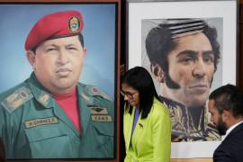 La presidenta encargada de Venezuela, Delcy Rodríguez, pasa ante una imagen del expresidente Hugo Chávez, a la izquierda, y el líder de independencia Simón Bolívar en la Asamblea Nacional de Caracas.