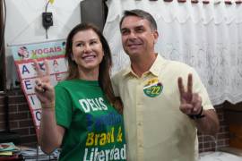El senador y candidato presidencial opositor Flavio Bolsonaro (a la derecha) y su esposa, Fernanda Bolsonaro, hacen la señal de la victoria tras votar en las elecciones generales en Río de Janeiro.
