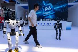 Un trabajador pasa junto a robots de la empresa china Lens en el China International Supply Chain Expo en Beijing, el 22 de junio de 2026.