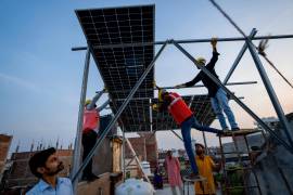 Varios trabajadores instalan paneles solares en el techo de una casa en Prayagraj, India, el lunes 14 de octubre de 2024.