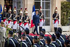El presidente francés, Emmanuel Macron (centro), llega para revisar las tropas mientras asiste a una ceremonia de bandera en el jardín del Palacio del Elíseo.