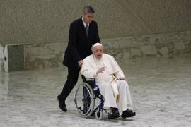El Papa Francisco llega en silla de ruedas para asistir a una audiencia con monjas y superiores religiosos en el Aula Pablo VI del Vaticano.
