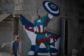 Un hombre pasa junto a un mural en Tel Aviv, Israel que representa al presidente estadounidense Joe Biden como un superhéroe que defiende a Israel.