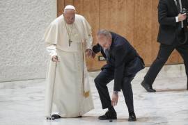 Un ayudante del papa Francisco se agacha para recoger una pieza del bastón del pontífice, a su llegada a una audiencia por el jubileo en el salón Pablo VI del Vaticano.