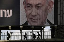Unas personas cruzan un puente bajo un anuncio de campaña televisiva en el que aparece el primer ministro israelí, Benjamin Netanyahu, de cara a las elecciones generales de Israel, en Ramat Gan, Israel.