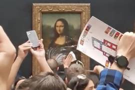 Un guardia de seguridad limpia crema de un pastel arrojado sobre el cristal que protege a la Mona Lisa en el Museo del Louvre en París, Francia.