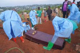Varias personas con equipos de protección colocan un ataúd con los restos de Baudjo Baraka Jules, de 6 años y que murió de ébola, en una tumba, en Bunia, en la provincia de Ituri, República Democrática del Congo.