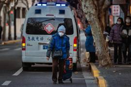 Una persona camina por la calle frente a una ambulancia, en Shanghái, China.
