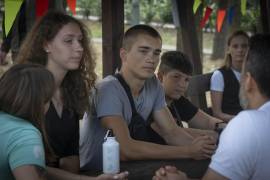 Valerii Soldatenko, de 16 años, de la región de Luhansk bajo ocupación rusa (c) y Kseniia Kucher, de 16 años, de Kharkiv (i) hablan con maestros en el campamento de rehabilitación para niños afectados por la guerra.