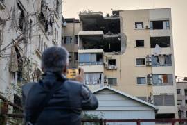 Un hombre toma fotos del daño en un edificio de apartamentos que fue impactado por un ataque aéreo israelí en Dahiyeh, un suburbio al sur de Beirut, Líbano.