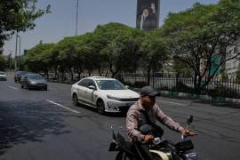 Vehículos enfrente de un cartel con el retrato del fallecido líder supremo iraní ayatolá Ali Jamenei, en Teherán, el 21 de julio del 2026.
