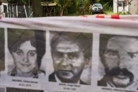 Oficiales del ejército observan desde el interior de la base militar de Campo de Mayo mientras los manifestantes sostienen una pancarta cubierta de imágenes de víctimas de la dictadura militar argentina.