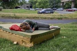 Stephanie W., de 28 años, que no tiene hogar, descansa en un colchón de espuma mientras pasa un vehículo de la Policía de Parques de EEUU, en el noroeste de Washington, cerca del Kennedy Center. FOTO: