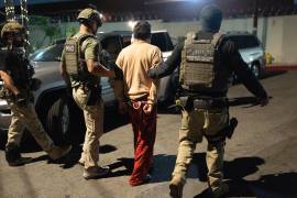 Policías escoltan a una persona acusada de votar ilegalmente en Commerce, California.