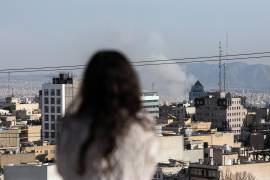 Una mujer observa cómo se eleva el humo tras un ataque con misiles en Teherán, Irán, el lunes 2 de marzo de 2026.
