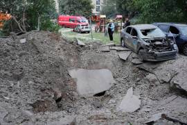 Residentes locales permanecen cerca de un cráter y de automóviles dañados por un ataque con misiles rusos en Kiev, Ucrania, el lunes 6 de julio de 2026. (Foto AP/Efrem Lukatsky)