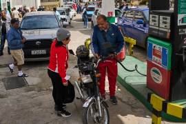 Un conductor reposta una motocicleta mientras otros conductores esperan en una larga fila en una gasolinera en La Habana, Cuba.