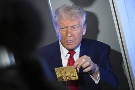 El presidente Donald Trump sostiene la tarjeta dorada de 5 millones de dólares mientras habla con la prensa durante un vuelo a bordo del Air Force One, rumbo a Miami.