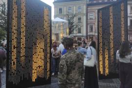 Varias personas buscan el nombre de sus familiares fallecidos en un memorial en Leópolis, Ucrania.