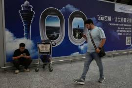 Un extranjero pasa junto a un cartel en el aeropuerto de Baiyun en Guangzhou, en la provincia sureña china de Guangdong.
