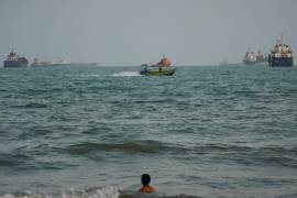 Una persona nada en la costa y al fondo se ven anclados buques en el estrecho de Ormuz, en Bandar Abbas, Irán, el 4 de septiembre 2026.