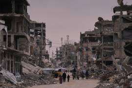 Palestinos caminan por una calle rodeada de edificios destruidos durante las operaciones aéreas y terrestres israelíes en Khan Younis, al sur de la Franja de Gaza, el jueves 22 de enero de 2026.