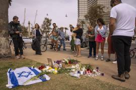 Un grupo de personas se congrega y coloca flores en el lugar donde murió el turista italiano Alessandro Parini en un ataque palestino, en Tel Aviv, Israel, el sábado 8 de abril de 2023.