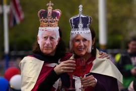 Dos personas posan con las máscaras del rey Carlos III y Camila, la reina consorte, en Londres, el viernes 5 de mayo de 2023 en los festejos previos a la coronación.
