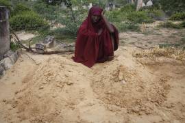 Fatuma Abdi Aliyow se lamenta junto a las tumbas de sus dos hijos muertos por enfermedades relacionadas con la desnutrición, en un campamento para desplazados en las afueras de Mogadiscio, Somalia.