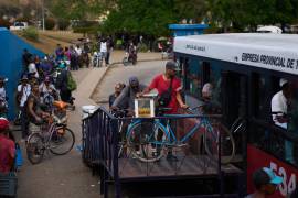 Varias personas suben sus bicicletas a un autobús público para cruzar el Túnel de la Bahía en La Habana, en Cuba.