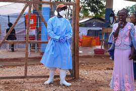 Residentes miran mientras trabajadores de la salud trasladan un ataúd con los restos mortales de una víctima de ébola, en el Centro de Tratamiento de Ébola del Hospital General de Bunia.