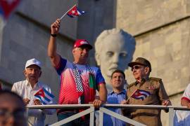 El presidente de Cuba Miguel Diaz-Canel ondea una bandera mientras mira el desfile del Día del Trabajo junto a Raúl Castro, segundo de derecha a izquierda, y Raul Guillermo Rodríguez Castro, nieto de Raúl Castro.