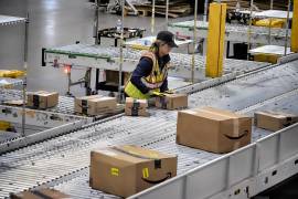 Un empleado de Amazon coloca paquetes en una cinta transportadora en una estación de entrega DAX7 de Amazon durante el evento anual Prime Day de Amazon en South Gate, California.