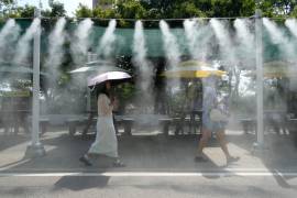 Unos visitantes pasan junto al dispositivo de nebulización refrescante en el sitio turístico de la cueva de Gwangmyeong, en Gwangmyeong, Corea del Sur, el 6 de agosto de 2026.