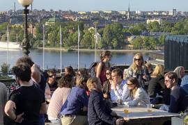 Personas disfrutan de bebidas y bocadillos en una terraza con vista a Estocolmo. Está prohibido fumar en las áreas interiores y exteriores de bares y restaurantes en Suecia.