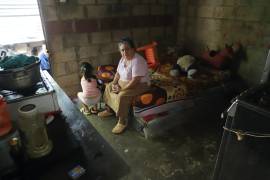 Jesús Esperanza Ventura, que ayuda en el cuidado de sus bisnietos, sentada en la cama de su nieta, Juana Guadalupe Recinos, en Santa Ana, El Salvador.