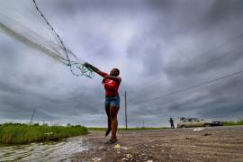 Con el cielo oscureciéndose ante la llegada de la tormenta tropical Bertha, Latia Ancar practica su técnica de pesca mientras ella y una amiga esperan la marejada ciclónica provocada por la tormenta.