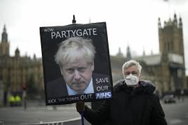 Un manifestante contrario al Partido Conservador sostiene una pancarta con la imagen del primer ministro británico, Boris Johnson, que alude a un escándalo sobre fiestas durante la cuarentena.