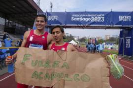Los mexicanos Emiliano Hernández (derecha) y Duilio Carrillo muestran un cartel de apoyo a Acapulco tras ganar la medalla de oro de los relevos masculinos del pentatlón moderno de los Juegos Panamericanos en Santiago.