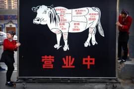Los trabajadores de un restaurante mueven un cartel que anuncia la gran inauguración de un restaurante de estofado de carne a lo largo de una calle de Beijing, el jueves 12 de octubre de 2017.