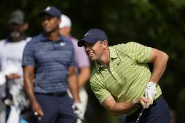 El norirlandés Rory McIlroy observa su tiro, delante de Tiger Woods, en la primera ronda del Campeonato de la PGA, el jueves 19 de mayo de 2022, en Tulsa, Oklahoma (AP Foto/Eric Gay)