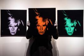 Un empleado de la casa de subastas Christie’s presenta tres autorretratos del artista estadounidense Andy Warhol a antes de salir a la venta, en Londres, Reino Unido, el 1 de marzo de 2018. EFE/Will Oliver