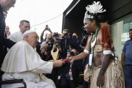 El papa Francisco entrega un regalo a un intérprete de bailes tradicionales a su llegada a APEC Haus, en Puerto Moresby, Papúa Nueva Guinea.