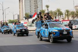 Vehículos de la policía iraquí, adornados con banderas nacionales y cintas, circulan en convoy para celebrar la retirada completa de las tropas estadounidenses de Irak, en Bagdad.