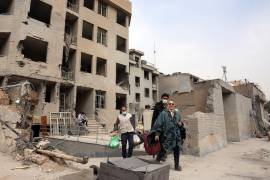 Los iraníes recogen sus pertenencias entre los escombros de sus edificios residenciales dañados en el centro de Teherán, Irán